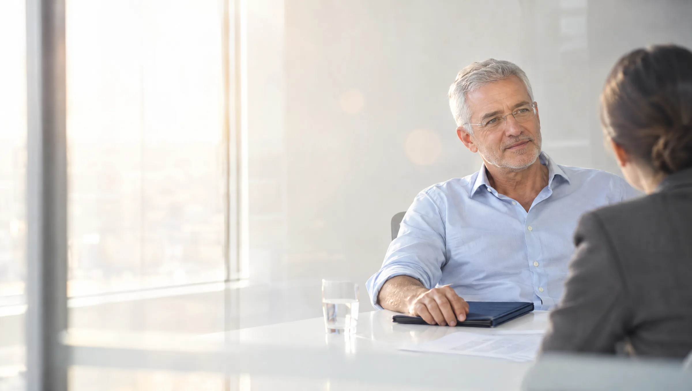A business owner in a quiet meeting with an advisor, seen through a glass wall